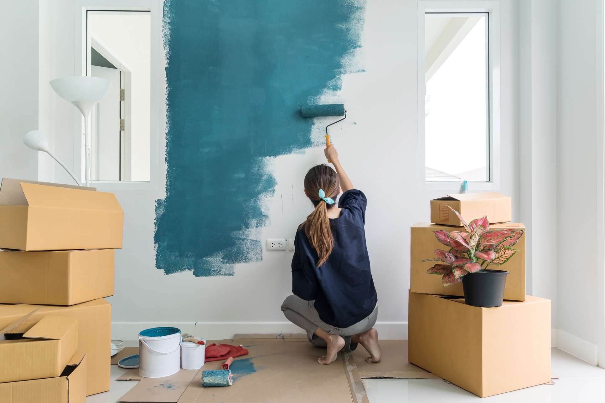 girl painting the wall inside a house